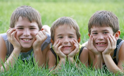 Stock image of three brothers lying next to each other in long grass